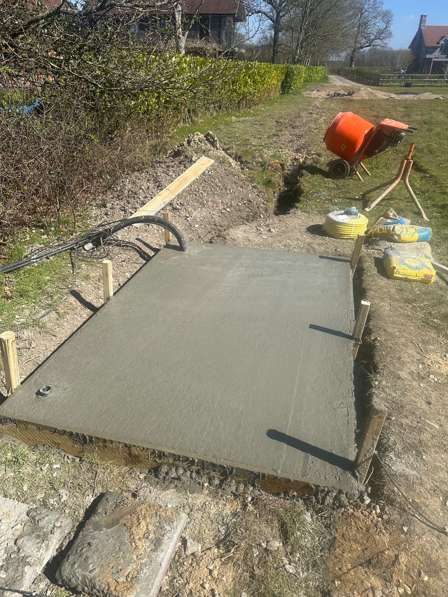 Freshly poured concrete base with ducted services ready for a garden building